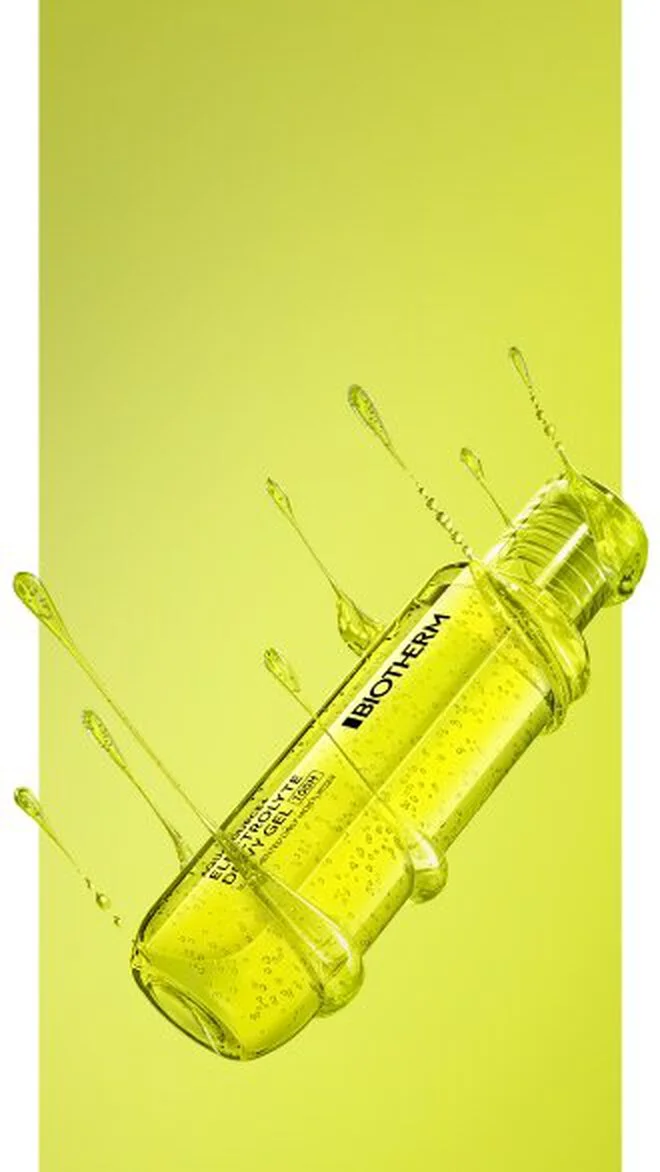 alt="Neon yellow-green transparent gel bottle floating diagonally mid-air with gel liquid splashing outward against a lime green background."